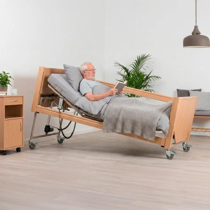 Hombre mayor leyendo cómodamente en una cama articulada eléctrica de madera